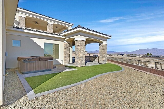 exterior space with a patio, a hot tub, ceiling fan, and a mountain view