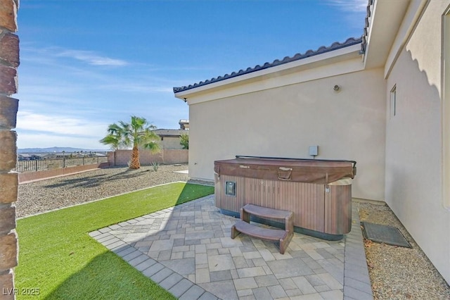 view of patio with a hot tub and fence