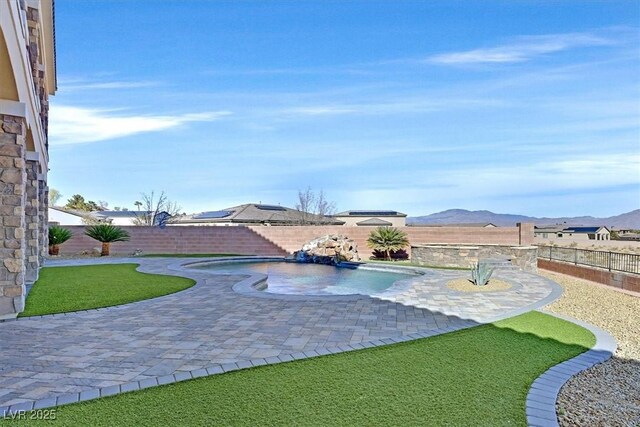 view of pool with a patio area, a lawn, and a mountain view