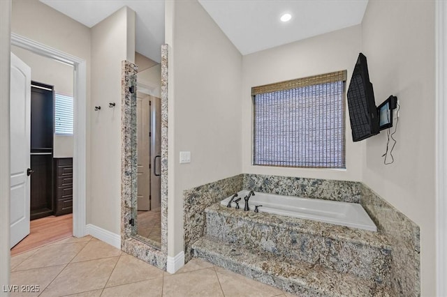 full bathroom featuring tile patterned floors, baseboards, a garden tub, and a stall shower