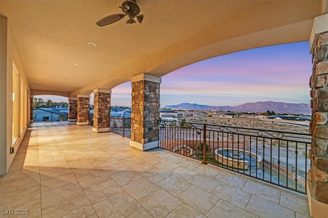 patio terrace at dusk with ceiling fan, a balcony, and a mountain view