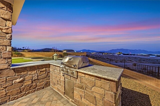 patio terrace at dusk with a grill, area for grilling, and a mountain view