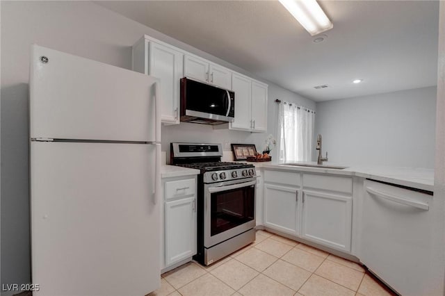 kitchen with appliances with stainless steel finishes, white cabinetry, light tile patterned floors, and sink