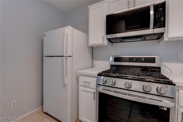 kitchen featuring stainless steel appliances, light stone countertops, light tile patterned floors, and white cabinetry