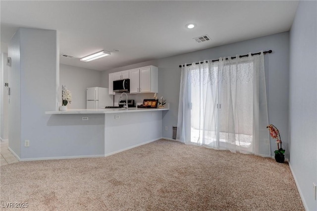 kitchen with a kitchen breakfast bar, light carpet, appliances with stainless steel finishes, kitchen peninsula, and white cabinetry