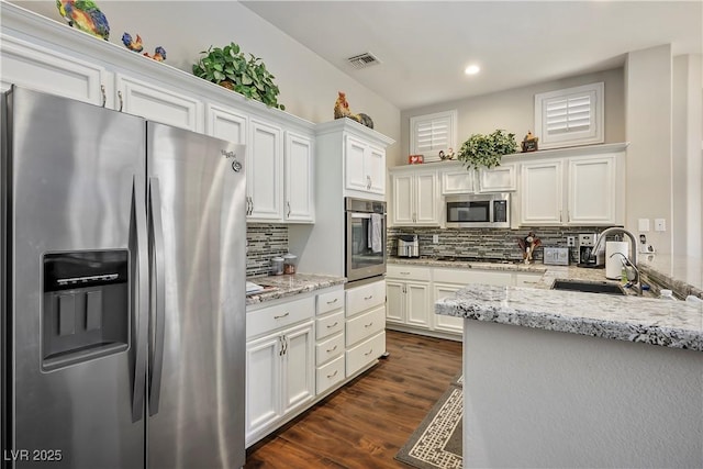 kitchen with decorative backsplash, appliances with stainless steel finishes, sink, and white cabinetry