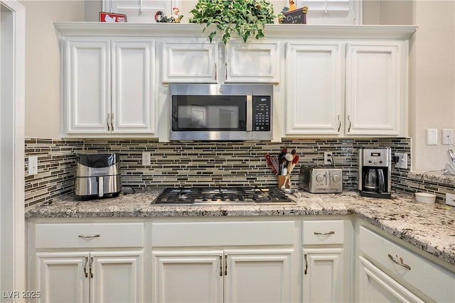 kitchen featuring stainless steel appliances, white cabinetry, and tasteful backsplash