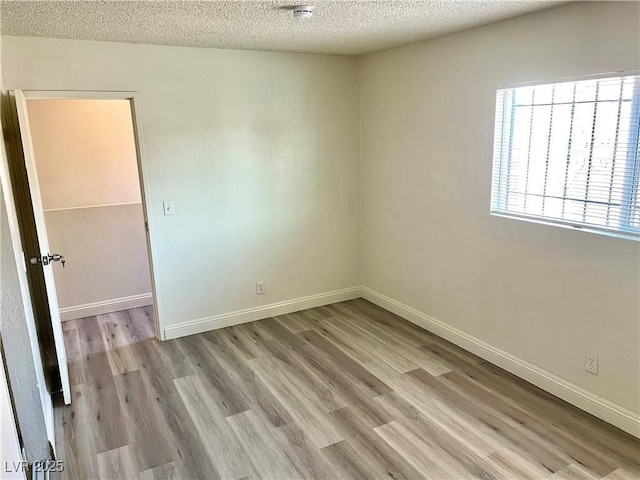 unfurnished room featuring a textured ceiling and light wood-type flooring