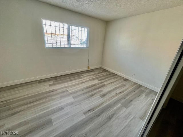 empty room featuring a textured ceiling and light hardwood / wood-style flooring