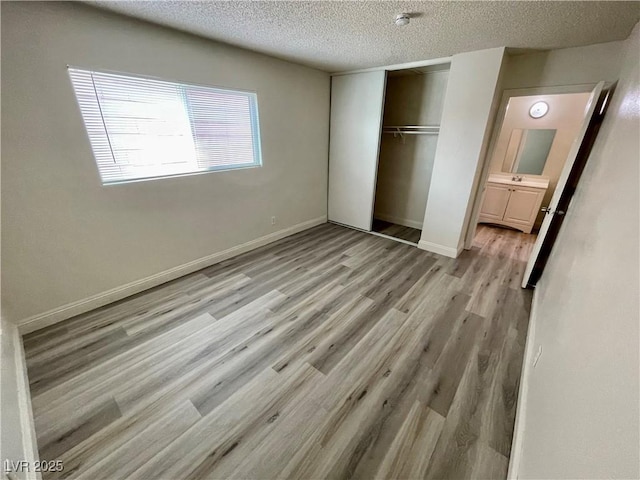 unfurnished bedroom with a textured ceiling, light wood-type flooring, and a closet