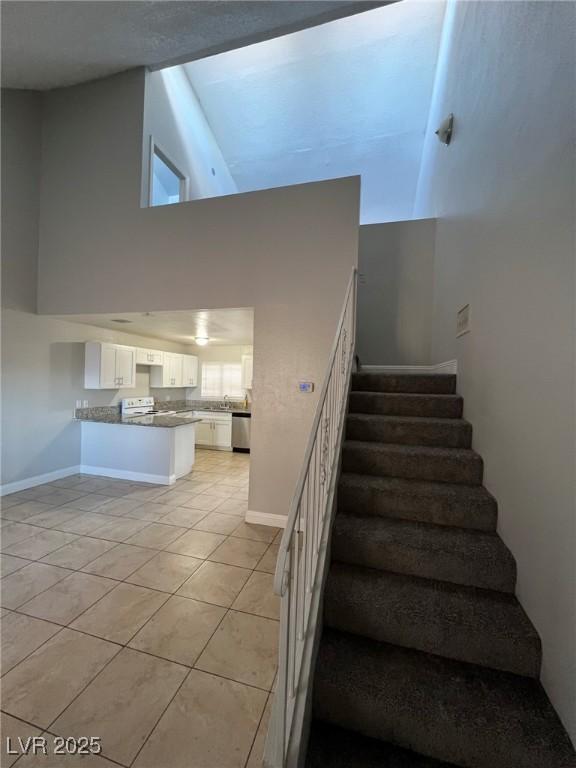 staircase with a towering ceiling and tile patterned flooring