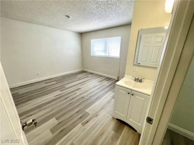 bathroom with a textured ceiling, wood-type flooring, and vanity