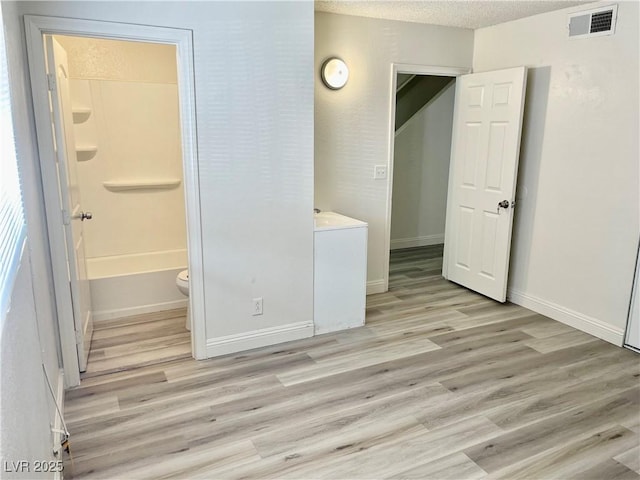 interior space featuring light wood-type flooring and a textured ceiling