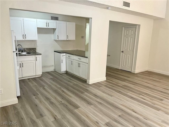 kitchen featuring white cabinets, white refrigerator, light hardwood / wood-style flooring, and sink