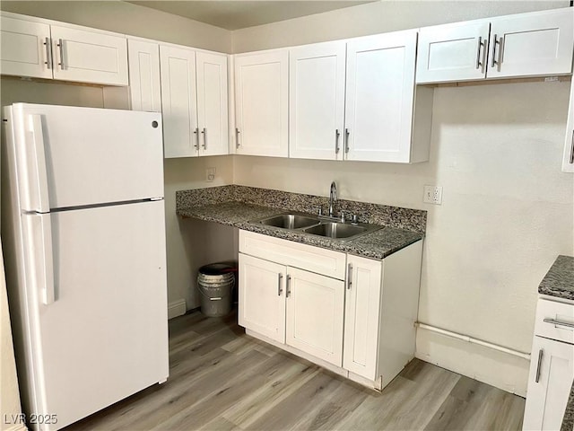 kitchen with white refrigerator, white cabinetry, and sink