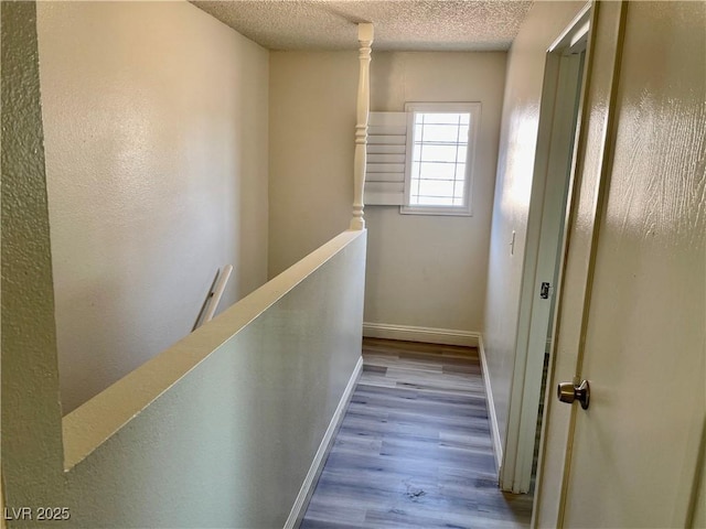 corridor featuring a textured ceiling and light wood-type flooring