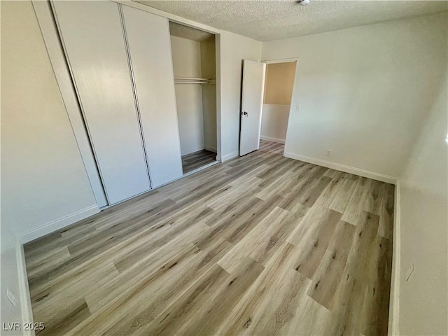 unfurnished bedroom with a textured ceiling, light hardwood / wood-style floors, and a closet