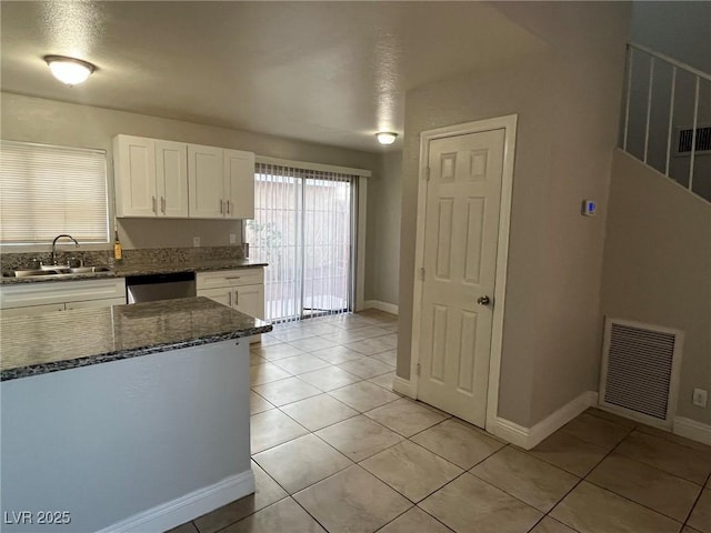 kitchen featuring sink, stainless steel dishwasher, white cabinetry, and light tile patterned flooring