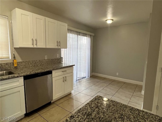 kitchen featuring dishwasher, dark stone countertops, light tile patterned floors, sink, and white cabinetry