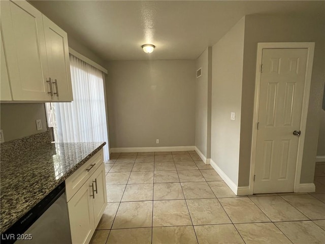 kitchen featuring light tile patterned flooring, white cabinetry, dark stone countertops, and dishwasher