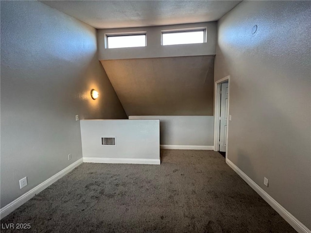 empty room featuring lofted ceiling and dark carpet