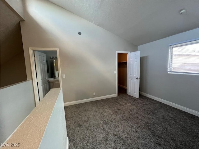 unfurnished room with lofted ceiling and dark colored carpet