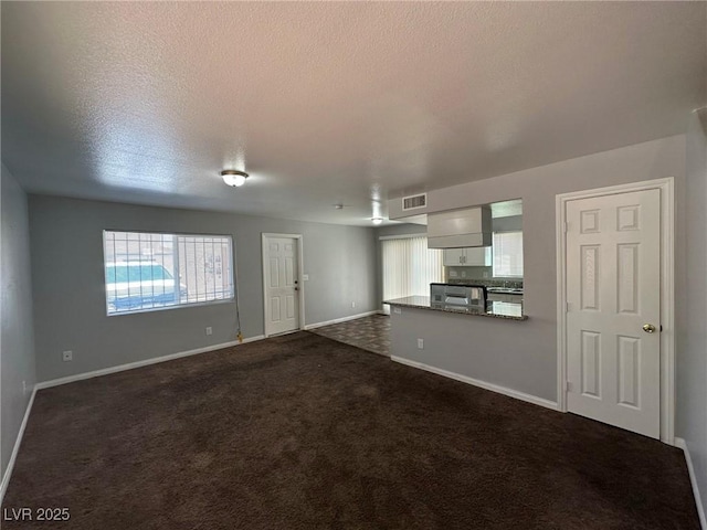 unfurnished living room featuring a textured ceiling and dark colored carpet