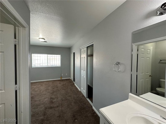 bathroom with a textured ceiling, vanity, and toilet