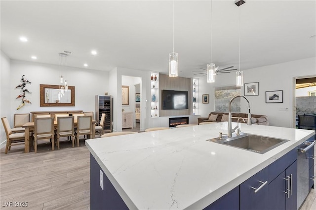 kitchen featuring pendant lighting, sink, a kitchen island with sink, ceiling fan, and blue cabinets