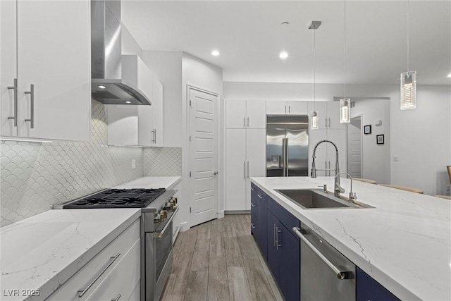 kitchen featuring white cabinetry, wall chimney range hood, high end appliances, pendant lighting, and sink