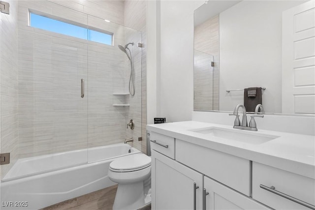 full bathroom featuring toilet, bath / shower combo with glass door, and vanity