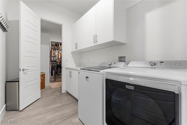 washroom with cabinets, washer and clothes dryer, and light hardwood / wood-style flooring