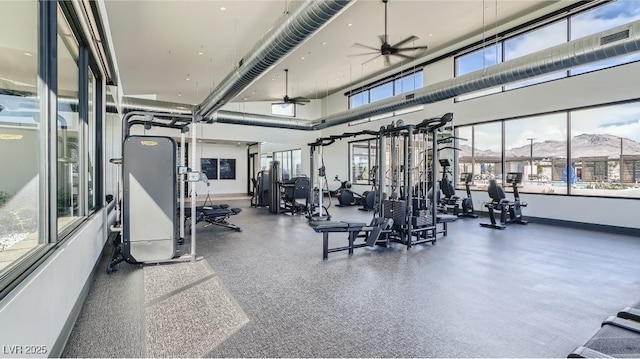 workout area with ceiling fan, a high ceiling, and a mountain view