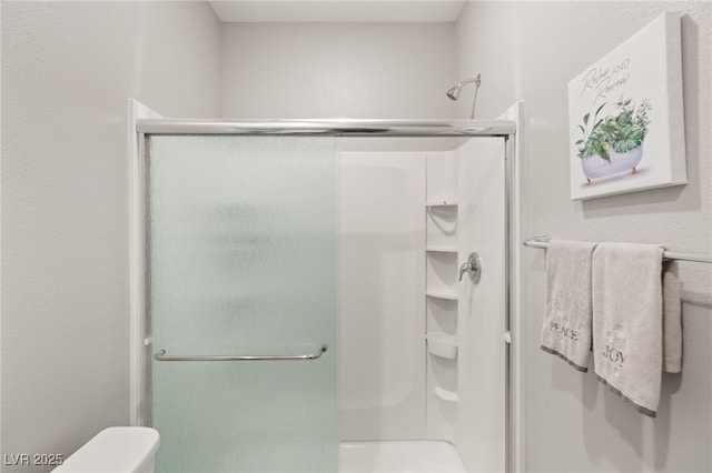 bathroom featuring walk in shower and toilet