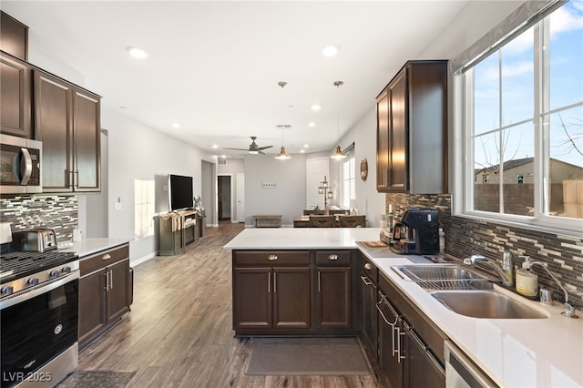 kitchen featuring sink, appliances with stainless steel finishes, ceiling fan, hanging light fixtures, and dark wood-type flooring