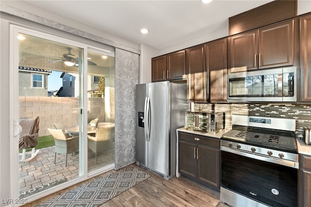 kitchen featuring stainless steel appliances, hardwood / wood-style floors, backsplash, and dark brown cabinetry