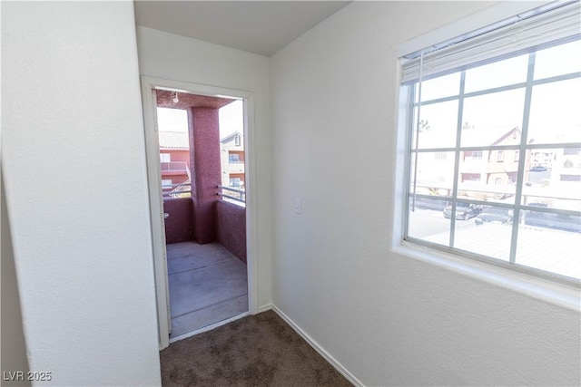 hall with dark colored carpet