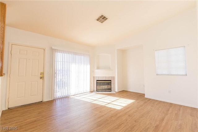 unfurnished living room featuring a tiled fireplace and light hardwood / wood-style flooring