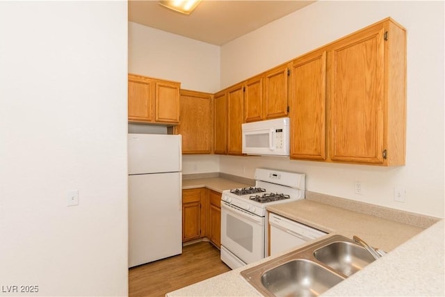 kitchen with sink, white appliances, and light hardwood / wood-style flooring