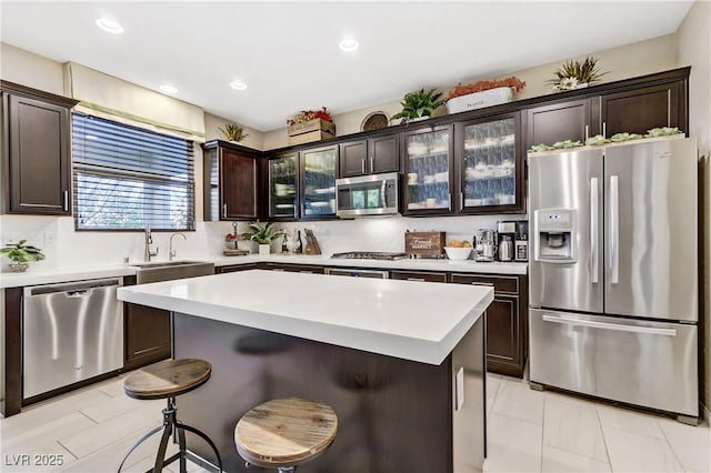 kitchen with a kitchen bar, appliances with stainless steel finishes, dark brown cabinetry, and a center island