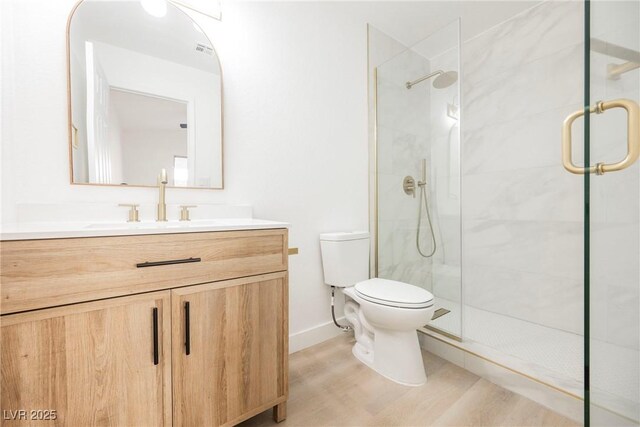 bathroom featuring toilet, hardwood / wood-style flooring, walk in shower, and vanity