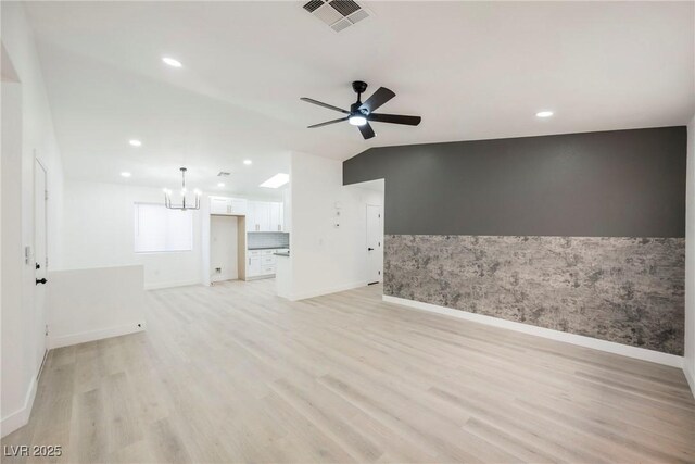 unfurnished living room with vaulted ceiling, light hardwood / wood-style floors, and ceiling fan with notable chandelier