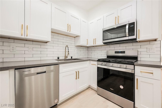 kitchen featuring appliances with stainless steel finishes, white cabinetry, tasteful backsplash, and sink