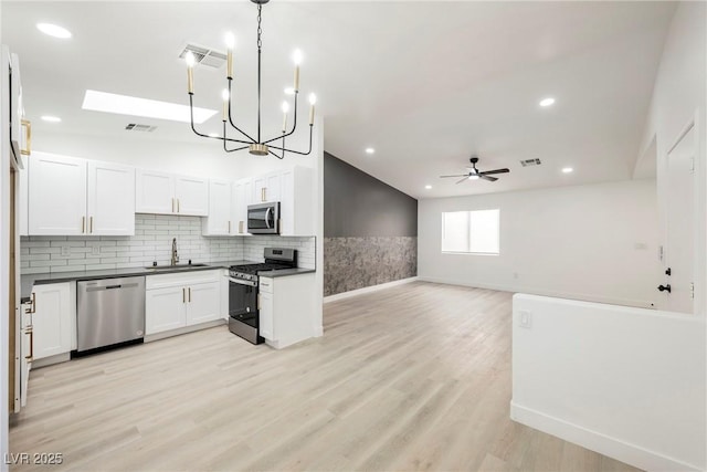 kitchen with white cabinets, stainless steel appliances, hanging light fixtures, ceiling fan, and sink