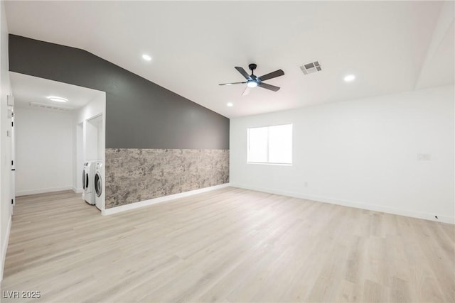 empty room featuring washer and dryer, vaulted ceiling, ceiling fan, and light hardwood / wood-style floors