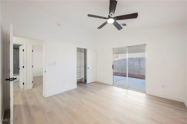 unfurnished bedroom featuring access to exterior, ceiling fan, light hardwood / wood-style floors, a closet, and a walk in closet