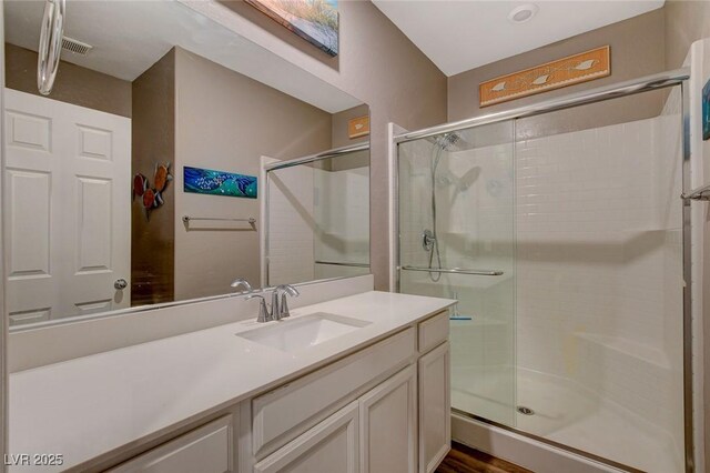 bathroom with a shower with door and vanity