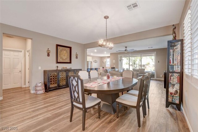 dining room with ceiling fan with notable chandelier and light hardwood / wood-style flooring