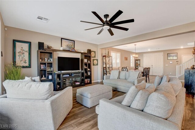 living room with ceiling fan with notable chandelier and hardwood / wood-style flooring