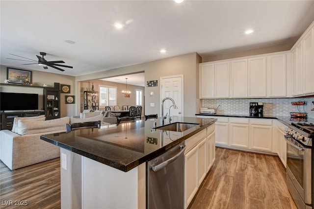 kitchen with sink, white cabinetry, light wood-type flooring, a center island with sink, and appliances with stainless steel finishes